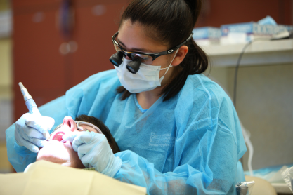 Dental hygiene student providing an oral exam. 