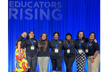 EdRising members and advisor in front of a blue curtain on stage. 