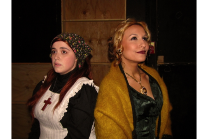 Two actresses in costume standing back to back.