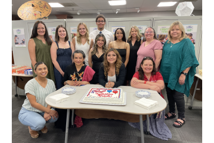 Group photo of graduates, faculty and staff from EVIT and MCC Early Childhood Education smiling in front of cake.