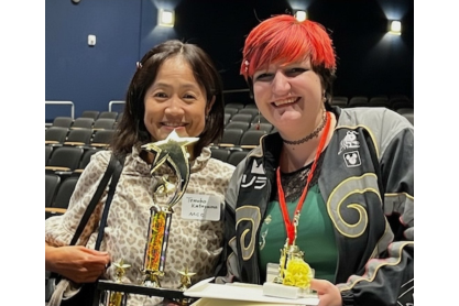 Aislynn Carpenter, on the right, holding the Grand Prize trophy, accompanied by Professor Tomoko Katayama, on the left..
