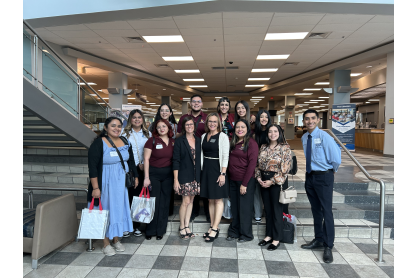 Twelve people gathered in two rows for a photo on interior staircase. MCC Global Education Symposium participants March 28, 2025. 