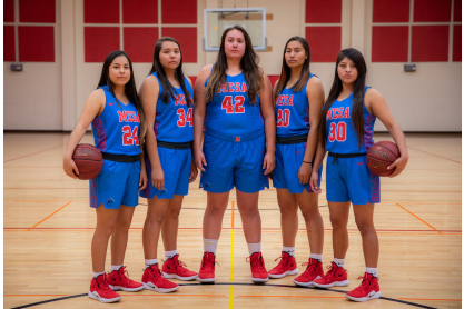 Five women's basketball players posing in uniform.