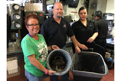 Three people holding bins