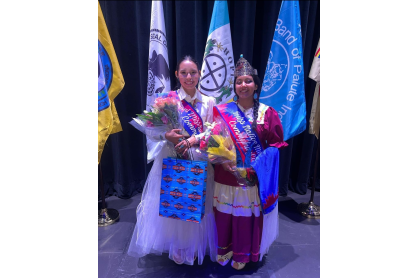 Two Native American women with sashes and a crown holding flowers