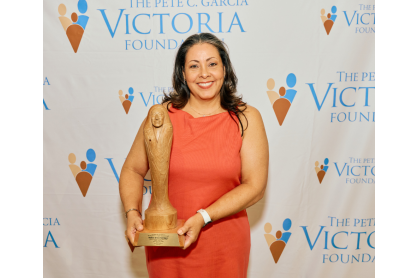 Woman in pink dress smiling holding award statue