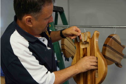 A faculty member assembles a wooden guitar.