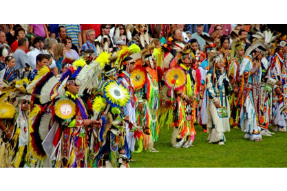 Group of American Indian performers in colorful traditional clothing.