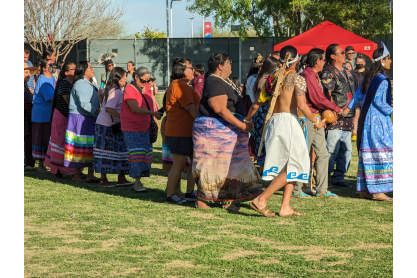 Line of people wearing traditional Native clothing and holding hands