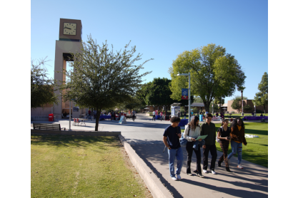Students walking on campus with the clock tower in background.