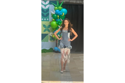 MCC student Allyson Ceron wearing her creation, a denim dress with denim roses around the top and bottom with lace at the knees, on the runway at Superstition Springs Mall event 2025. 