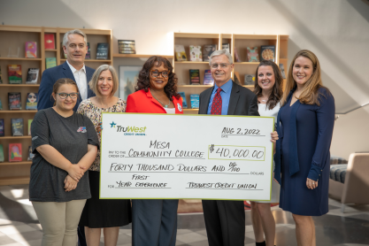 Seven people, MCC and TruWest Credit Union representatives standing behind a large replica of a check for $40,000. 