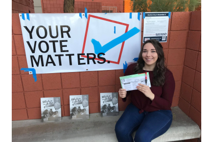 MCC student Shelby Lynch holding a ballot next to a poster that reads Your Vote Matters. 