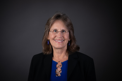 Yvonne wearing a royal blue shirt and a dark suit jacket. 