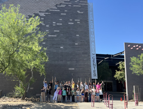 Group of flutists in front of the MCC Performing Arts Center having fun with flutes mostly pointed up