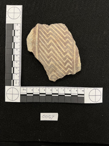 A pottery sherd on a black background with a measurement reference