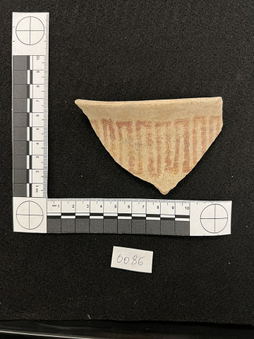 A pottery sherd on a black background with a measurement reference