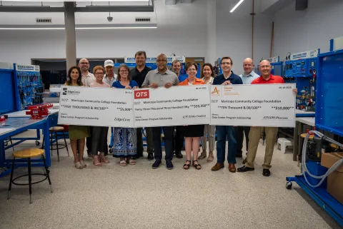 Thirteen people, representatives from MCC, Maricopa Community Colleges Foundation, EdgeCore, QTS and the Phoenix AFCOM Chapter standing behind three oversized checks representing the donations to the new Data Center Operations scholarship Fund. 