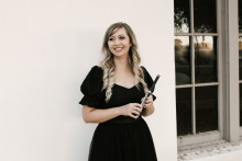 Abby Coffey in a black dress holding a piccolo