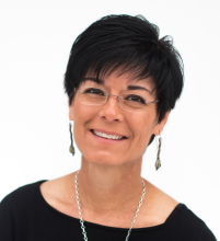 Niccole Cerveny, Ph.D. head and shoulders photo. She has short black hair and is wearing minimalistic eyeglasses and a black scooped-neck top. 