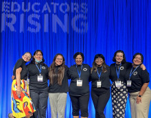 EdRising members and advisor in front of a blue curtain on stage. 