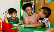 A teacher sitting a table with two young children