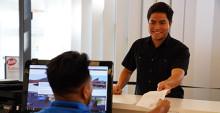 Student handing papers to a staff member