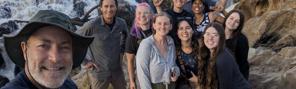 Dennis Wilson and students pose near a waterfall.