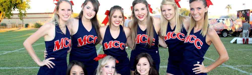 Group of MCC cheerleaders smiles on the football field.