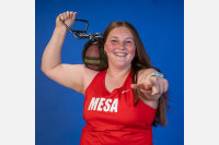 Maleah Tucker holding track equipment wearing a red Mesa shirt