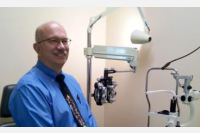  Close up of Dr. James Abbott posing next to optometry equipment
