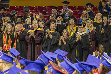 Faculty members applaud graduates.