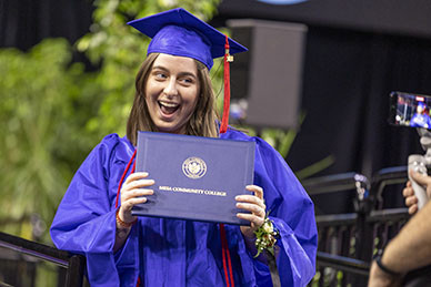 A graduate poses for a photo with her diploma cover.
