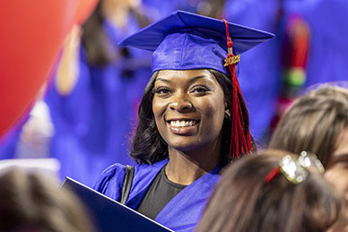 A graduate smiles in the crowd at graduation.
