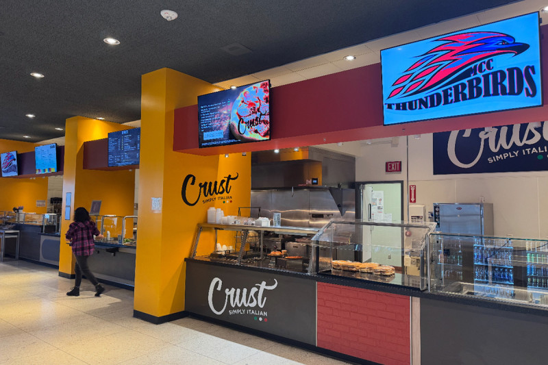 A cafeteria counter with menu displays hanging above.
