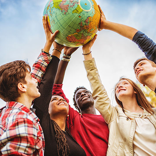 Five students holding a globe in the air.