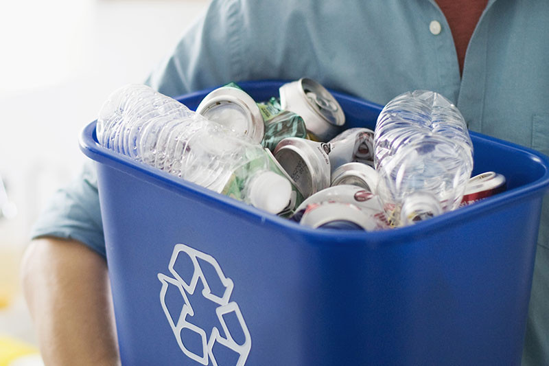A full recycling bin being held up.