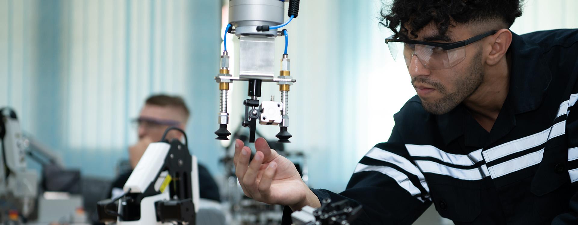 A person with protective glasses working a robotic arm.