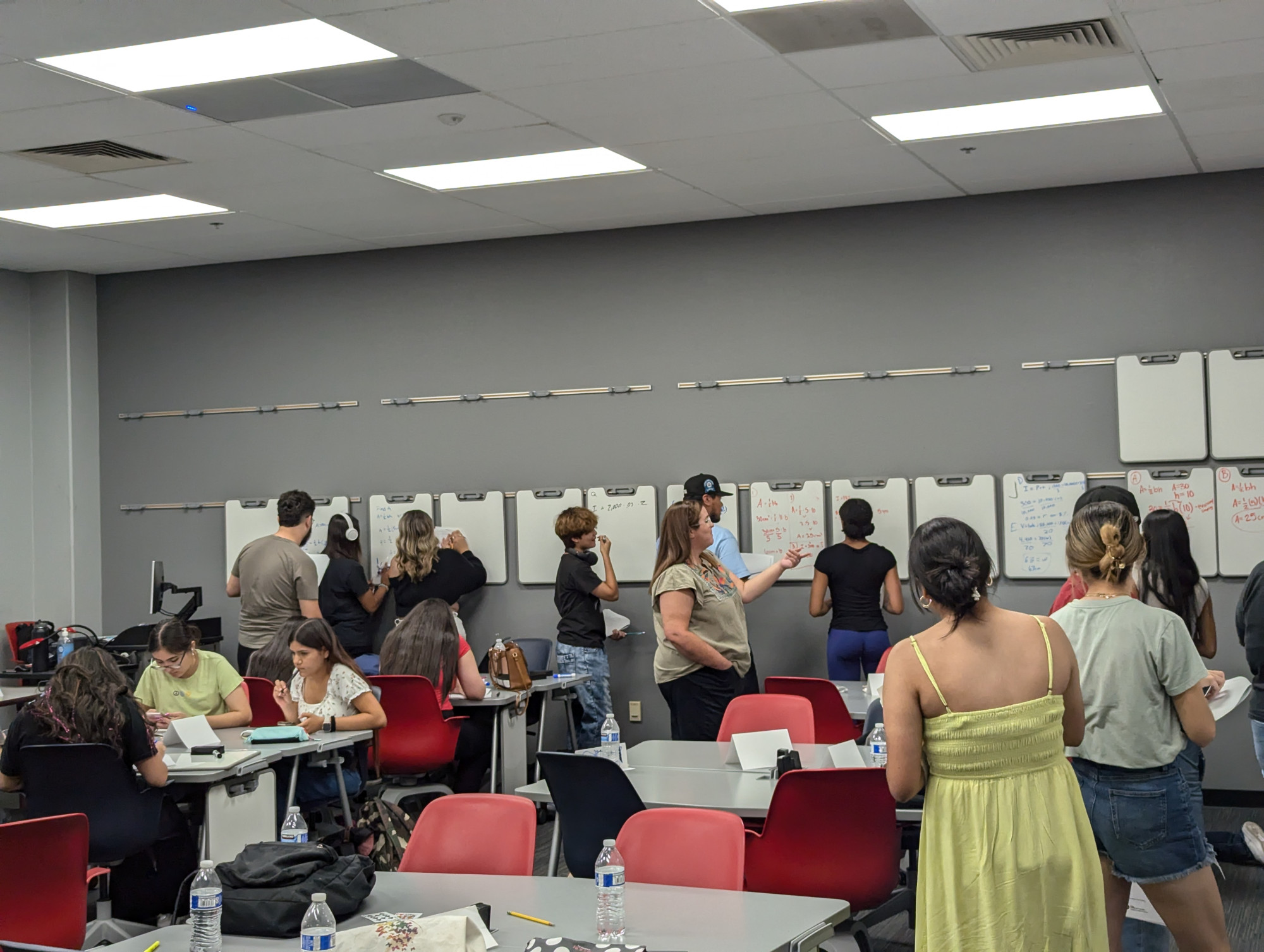 Students gather at whiteboards to solve problems.