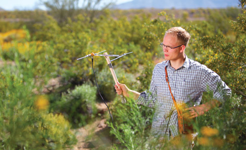 An instructor holding a pole with metal sensors outside.