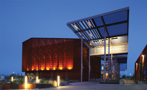 A campus building lit up at night with a large awning in front.