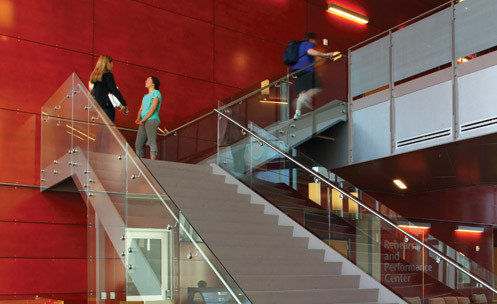 An indoor staircase with two students talking on a landing.