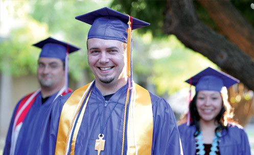 Three students in caps and gowns outside.