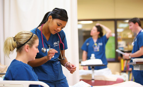 Students in scrubs in a medical setting.