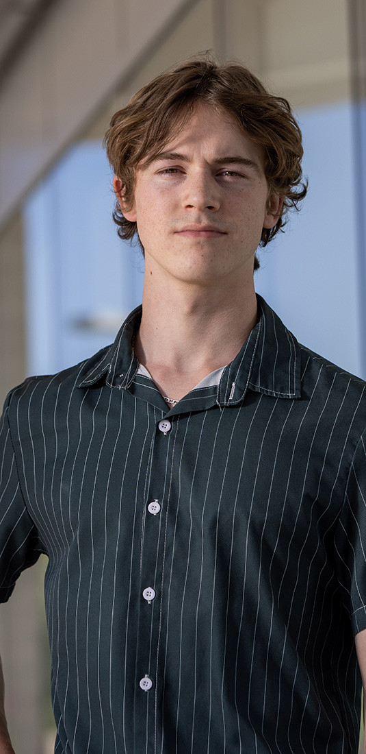 Male student in a striped button shirt smiling.