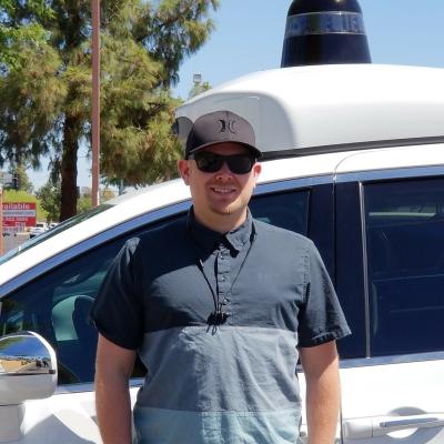 Shelby Prockish posing in front of a Waymo car.