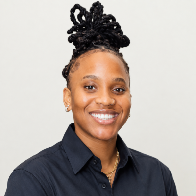 Peace Amukamara wearing a black button up shirt and hair in a bun