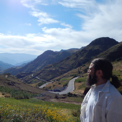 Man looking in distance at landscape of mountains and winding road