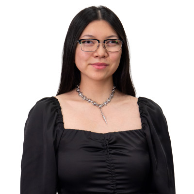 Woman wearing a black dress, necklace and wearing glasses.