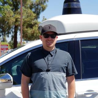 Shelby Prockish posing in front of a Waymo car.